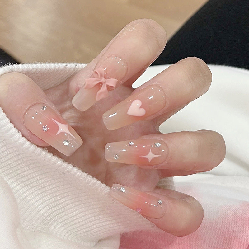 Artificial nails with heart design and glitter accents 
Maetiva
