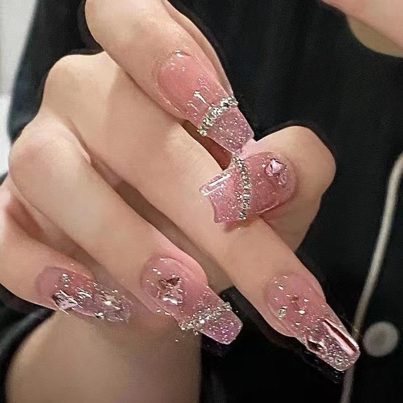 Artificial nails with heart design and glitter accents 
Maetiva