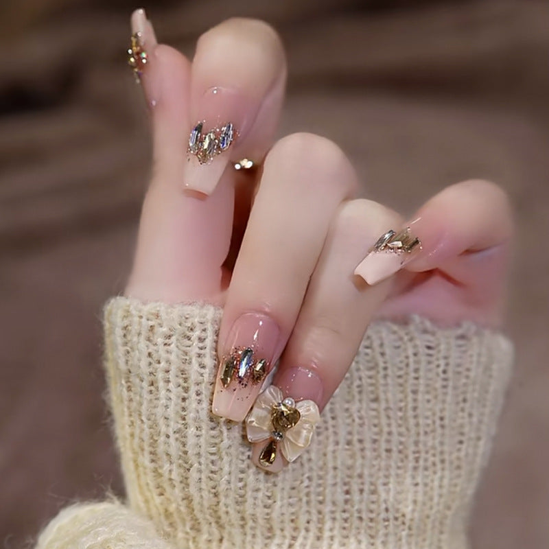 Artificial nails with heart design and glitter accents 
Maetiva