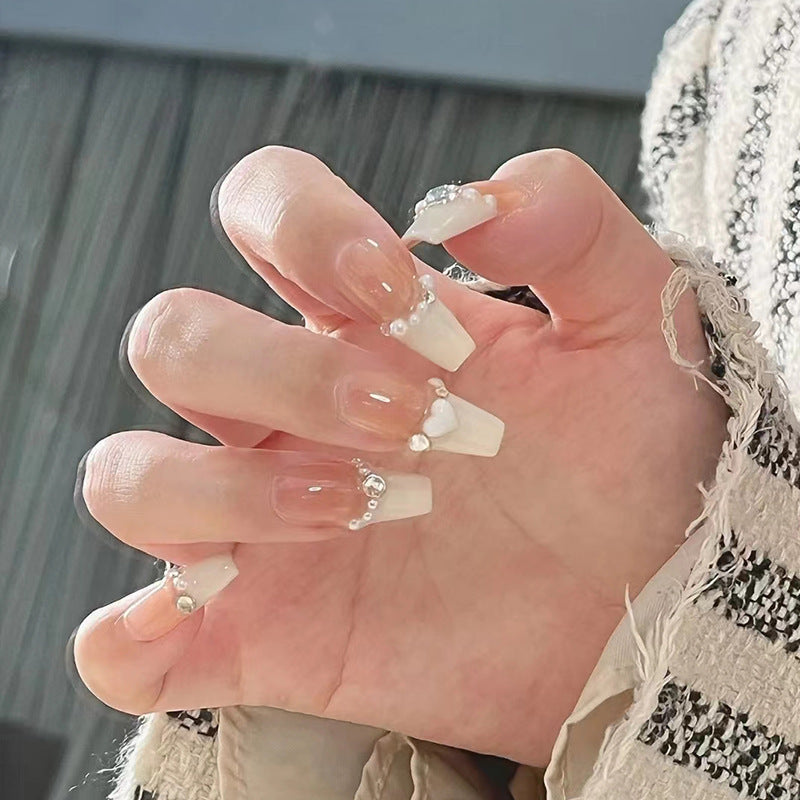 Artificial nails with heart design and glitter accents 
Maetiva