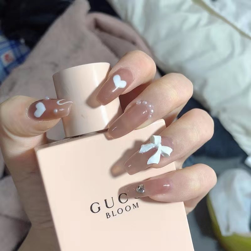 Artificial nails with heart design and glitter accents 
Maetiva