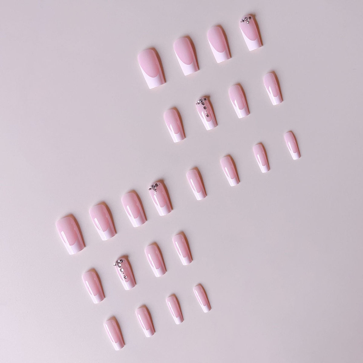 Acrylic nail set with elegant French tips and sparkling rhinestone accents 
Maetiva