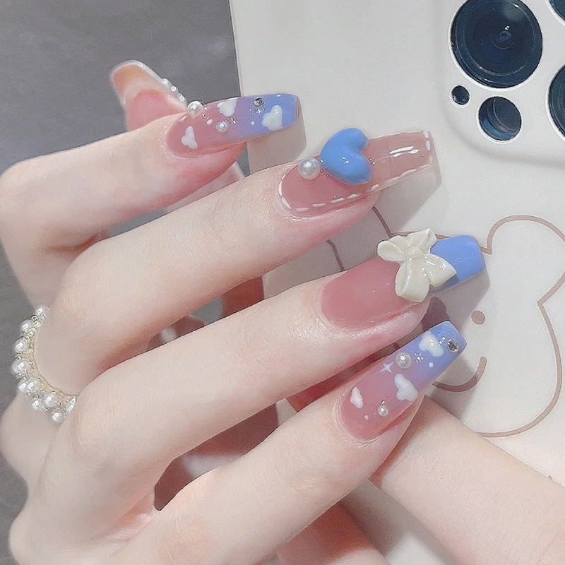 Artificial nails with heart design and glitter accents 
Maetiva